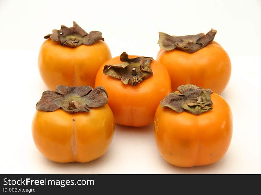 Five persimmons arranged as on dice, on a white surface and background. Five persimmons arranged as on dice, on a white surface and background