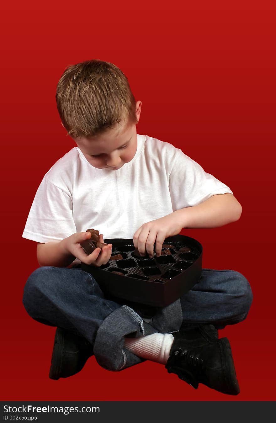 A little boy picking a handful of candy from the box. A little boy picking a handful of candy from the box.