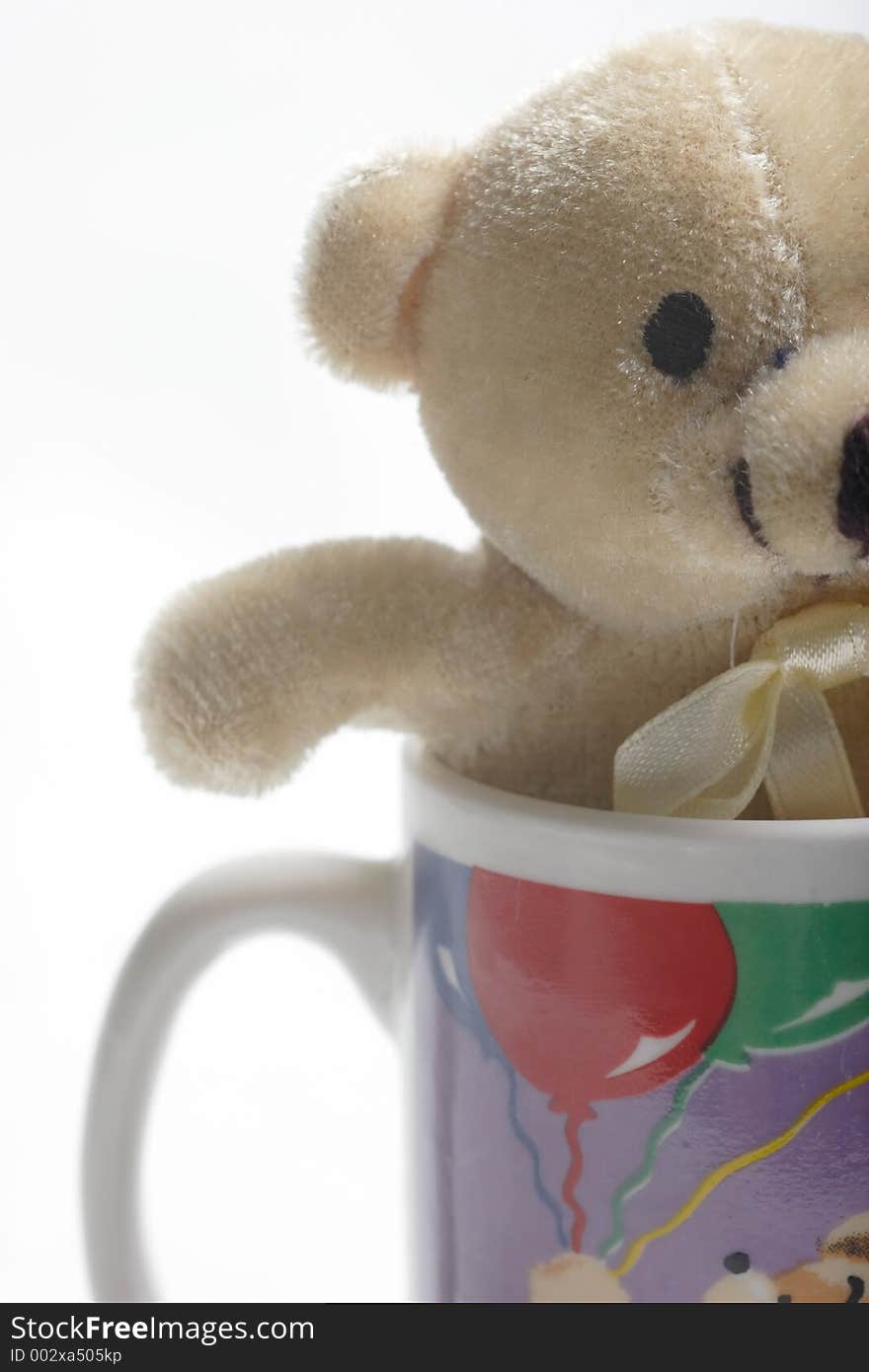 Small teddy bear in a coffee cup up close on white