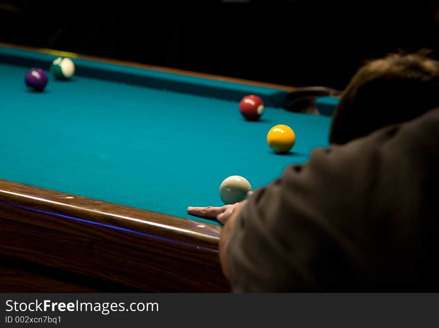 A pool player lines up to make his shot. Focus on cue ball. A pool player lines up to make his shot. Focus on cue ball.