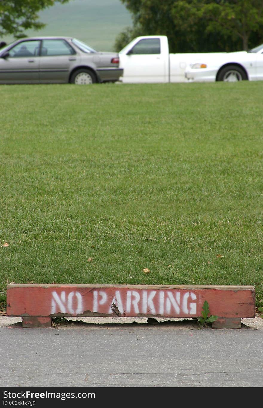 A wooden marker warns against parking near the grass. A wooden marker warns against parking near the grass.