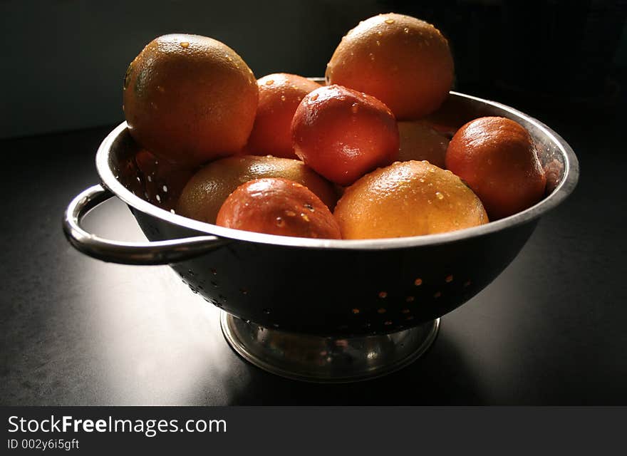 Bunch of citrus in a colander in window light. Bunch of citrus in a colander in window light