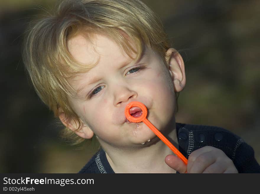 2 year old boy trying to blow bubbles at park. Model released. 2 year old boy trying to blow bubbles at park. Model released