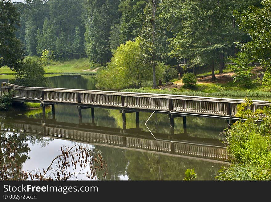 A wooden bridge over a peaceful pond