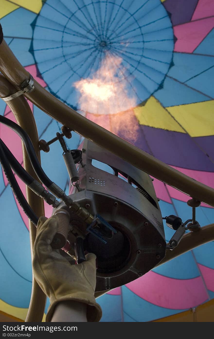 Balloon pilot's gloved hand firing the jet in a colorful hot air balloon. Balloon pilot's gloved hand firing the jet in a colorful hot air balloon