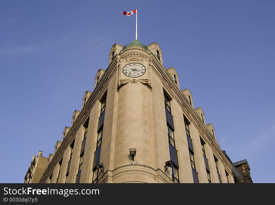 Distorted Perspective of a wedge shaped building, clock face and Canadian flag at the top