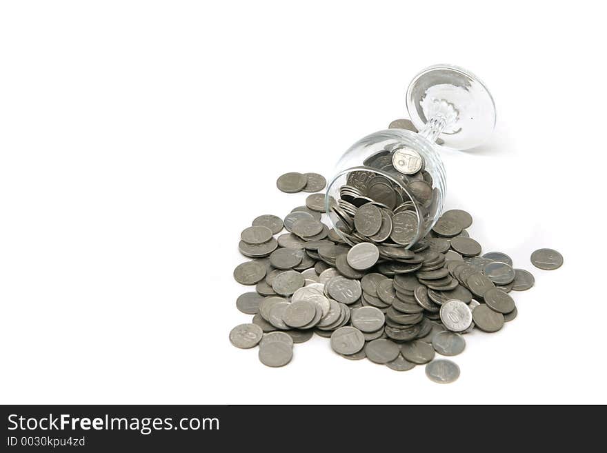 Wineglass with coins poured out over a white background. Wineglass with coins poured out over a white background