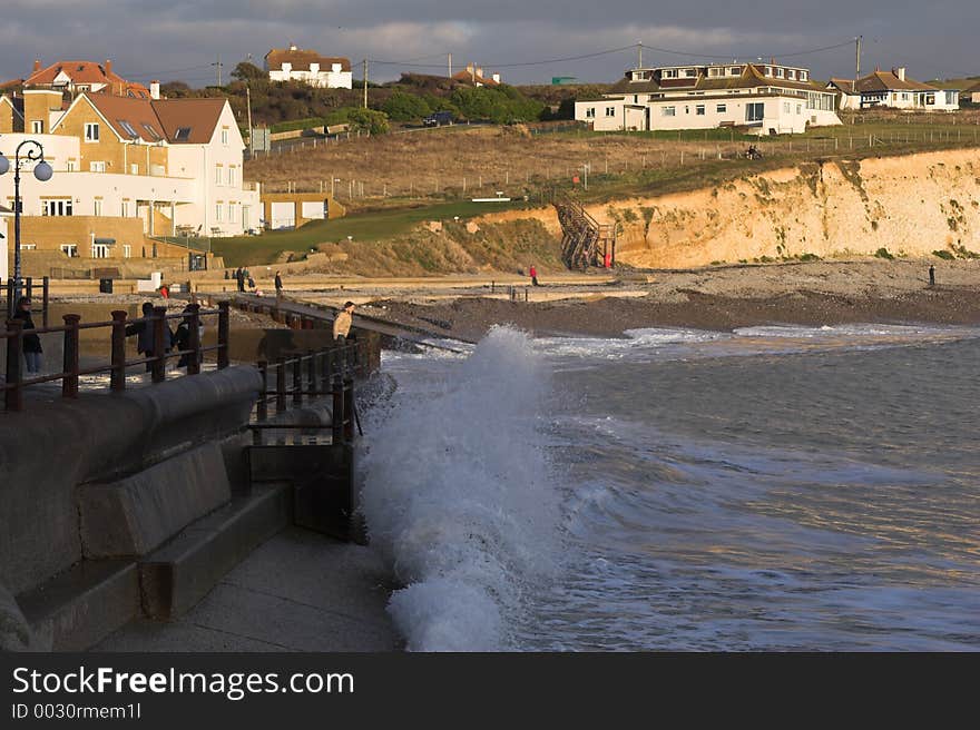 Girl with wave crashing into sea wall