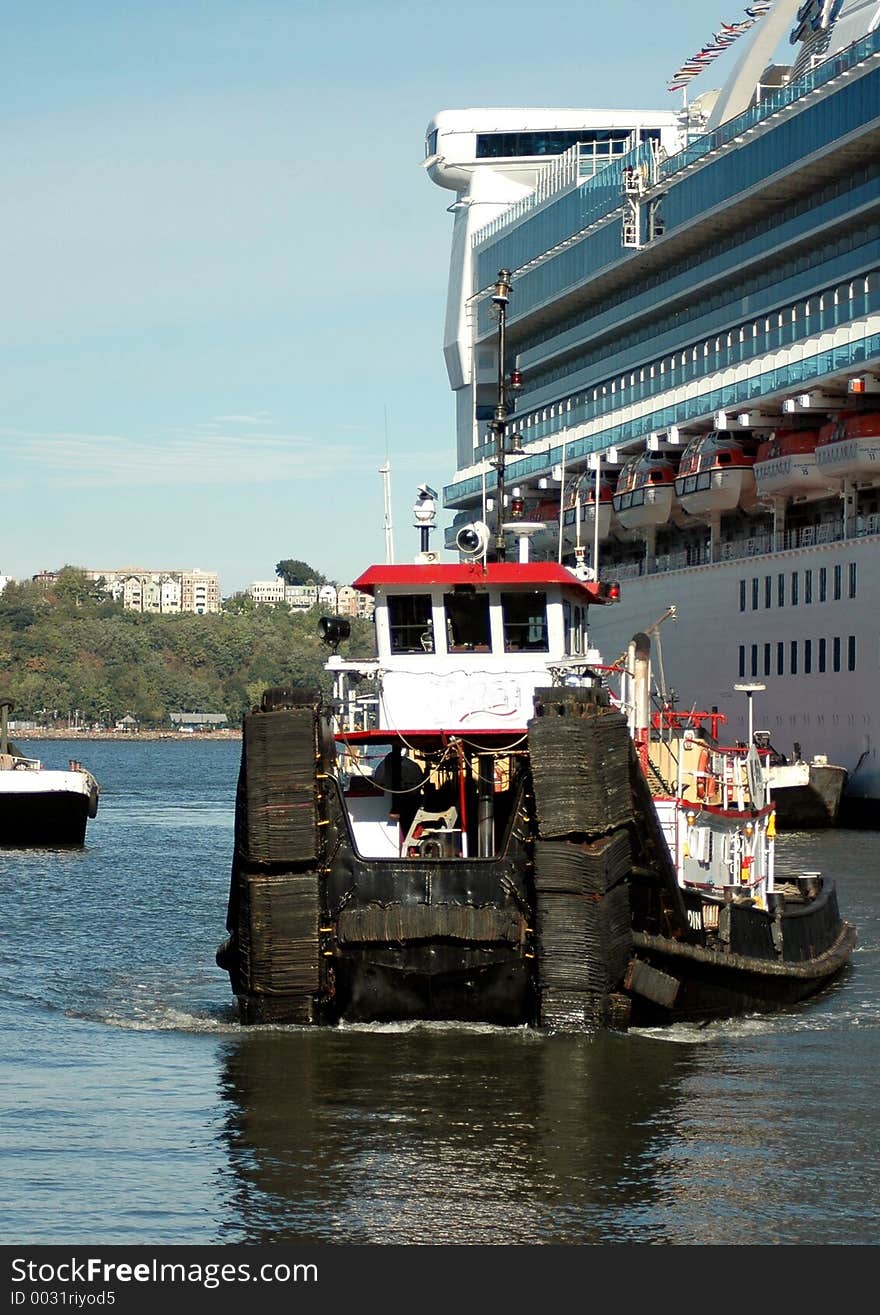 Barge helping cruise ship into port.