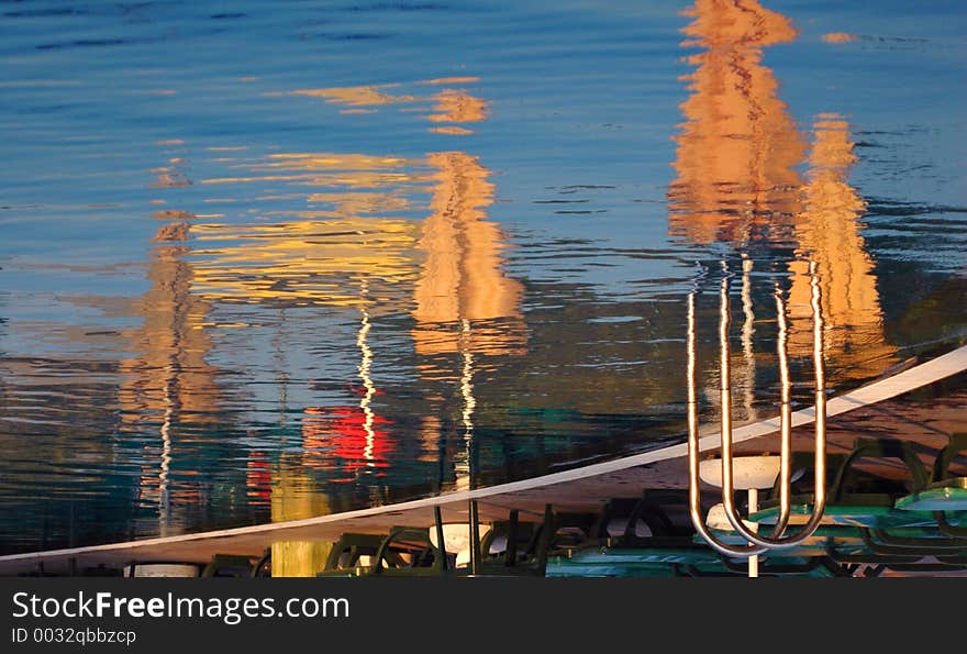 Reflections of sun umbrellas in a pool, waiting people at the beach. Shot at dawn. Conceptual shot for end of spring, start of the summer season. Can work well for end of season too. Reflections of sun umbrellas in a pool, waiting people at the beach. Shot at dawn. Conceptual shot for end of spring, start of the summer season. Can work well for end of season too.