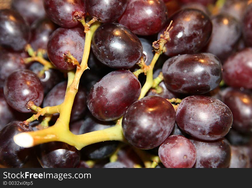 A closeup of a bunch of juicy red grapes ripe on the stem.