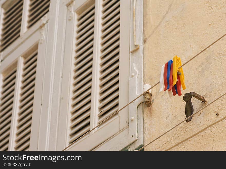 Clothesline and Clothespins on the outside of a building- shutters in the background