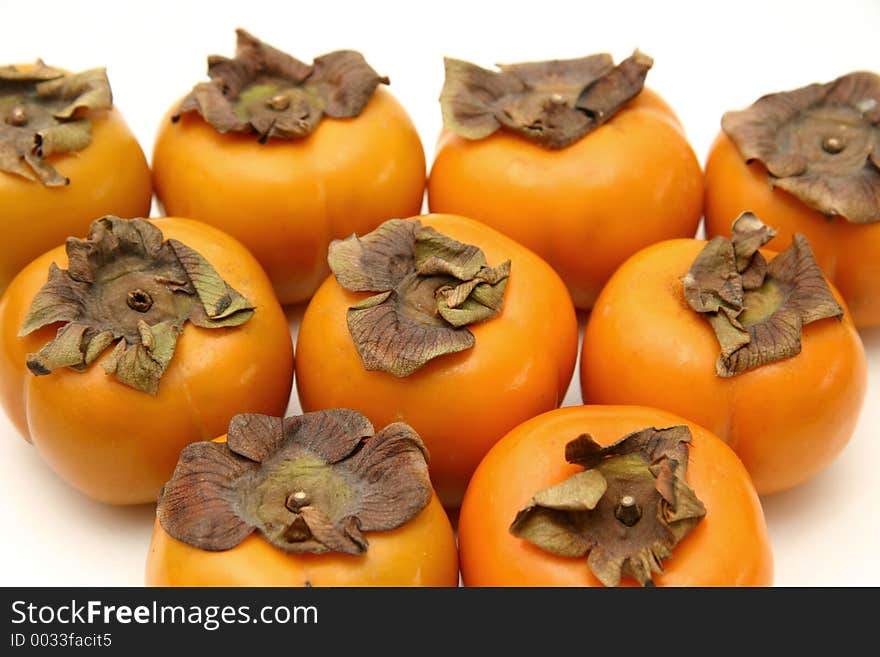 A layout of persimmons arranged in a triangle on a white surface and background