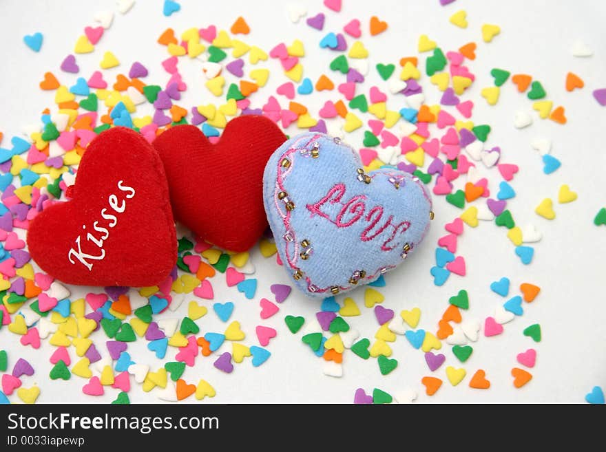 Three small soft spongy cushioned hearts sprinkled with multi colored candied hearts. Three small soft spongy cushioned hearts sprinkled with multi colored candied hearts