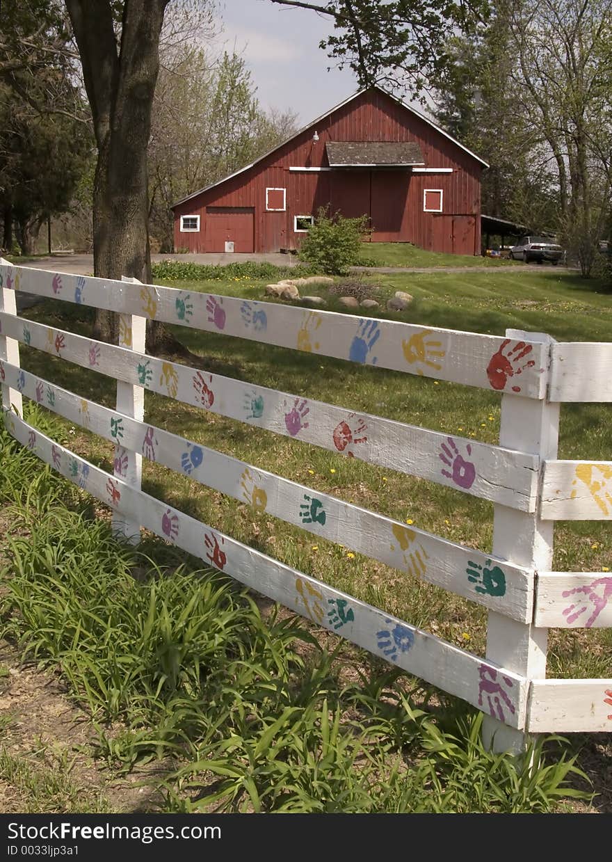 Colorful Hand prints on a white fence- barn in background