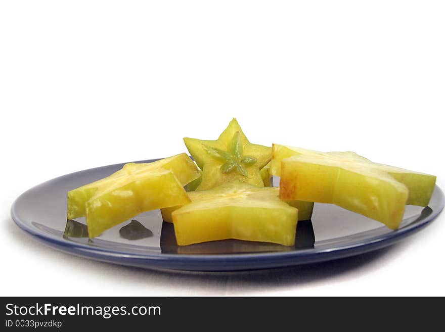 Pieces of starfruit organized neatly on a blue ceramic plate. Pieces of starfruit organized neatly on a blue ceramic plate