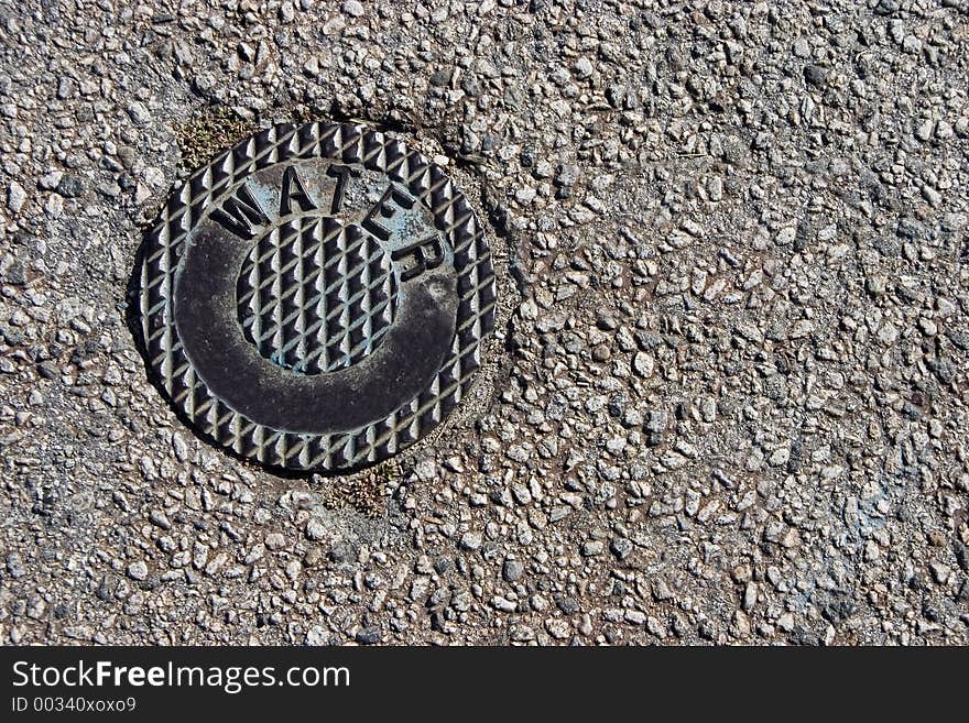 A metal cover on the street, protecting a water department valve. A metal cover on the street, protecting a water department valve.