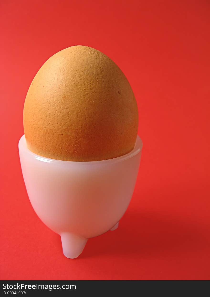 Soft-boiled egg in a white egg cup over red background