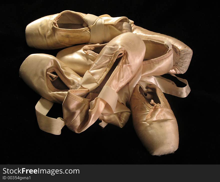 A pile of pink pointe shoes isolated on a black background. A pile of pink pointe shoes isolated on a black background