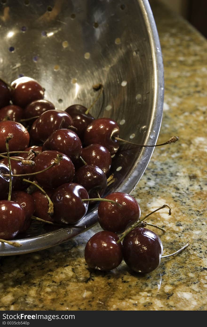 Freshly picked and washed cherries fall from the colander, ready to be eaten. Freshly picked and washed cherries fall from the colander, ready to be eaten.