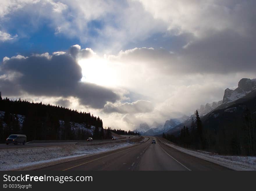 A horizontal shot of a beautiful, dramatic sky over top a mountain highway. A horizontal shot of a beautiful, dramatic sky over top a mountain highway.