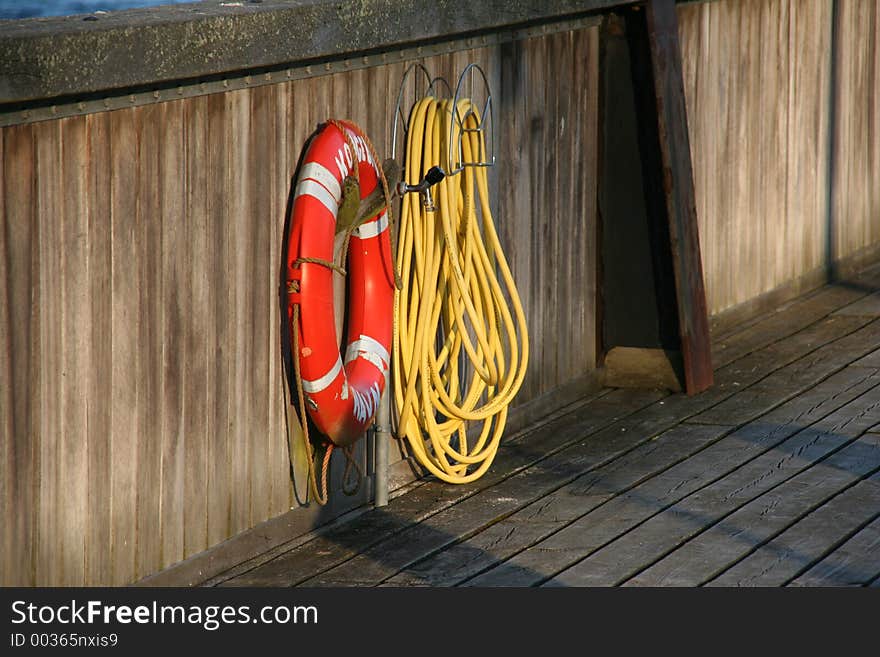 Lifebelt and hose at a small harbour in the eventing sun. Lifebelt and hose at a small harbour in the eventing sun