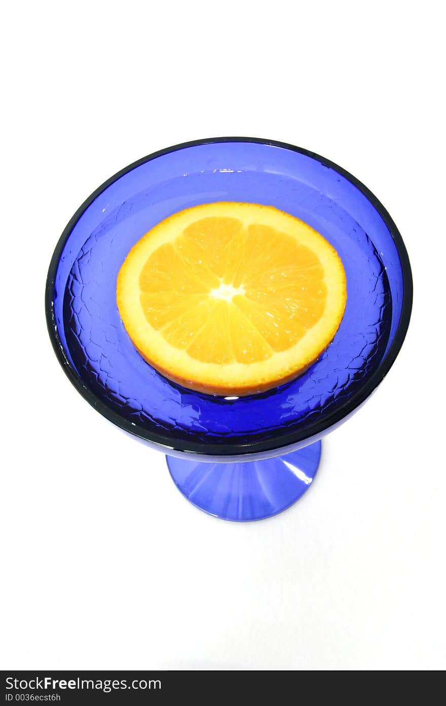 Half an orange floats in a blue glass. Half an orange floats in a blue glass