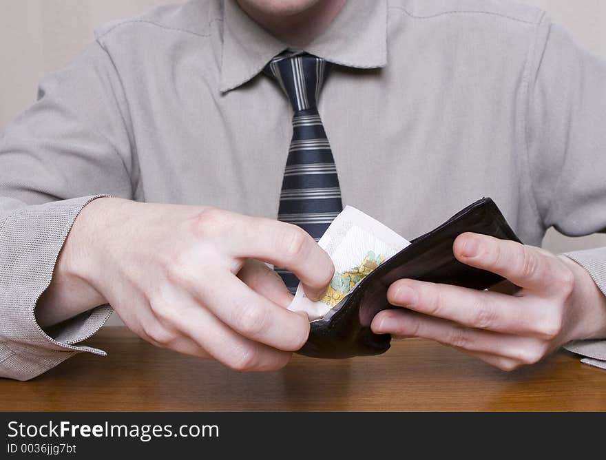 Man, getting notes out of his wallet, paying for an item. Man, getting notes out of his wallet, paying for an item