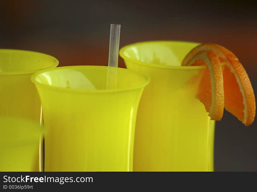 Bright yellow cocktail glasses with orange slice garnish. Bright yellow cocktail glasses with orange slice garnish