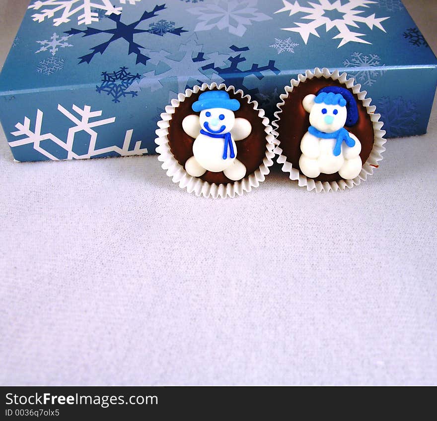 Snowman on chocolate against a box of chocolates, with snowflakes. Snowman on chocolate against a box of chocolates, with snowflakes.