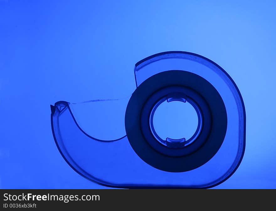 Transparent tape dispenser on blue background. Transparent tape dispenser on blue background