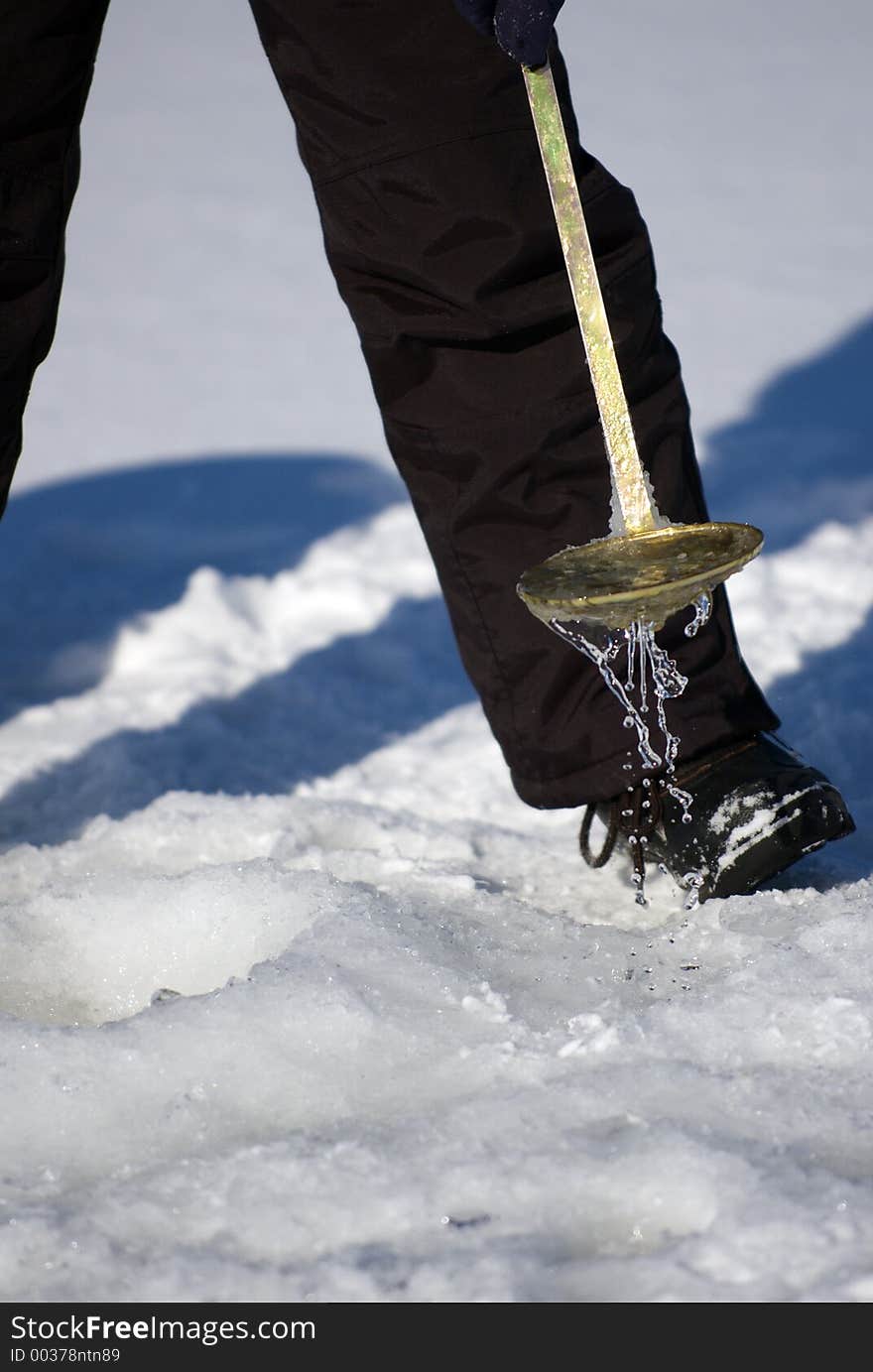 Ice fisherman dipping ice out of ice hole. Ice fisherman dipping ice out of ice hole