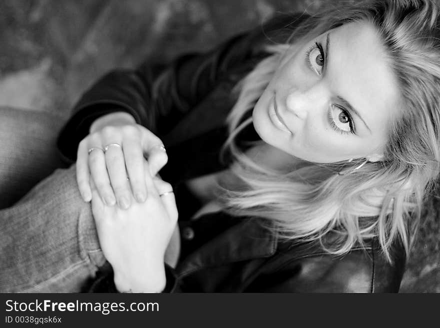 A young woman looking in the camera, holding her knee, black and white. A young woman looking in the camera, holding her knee, black and white