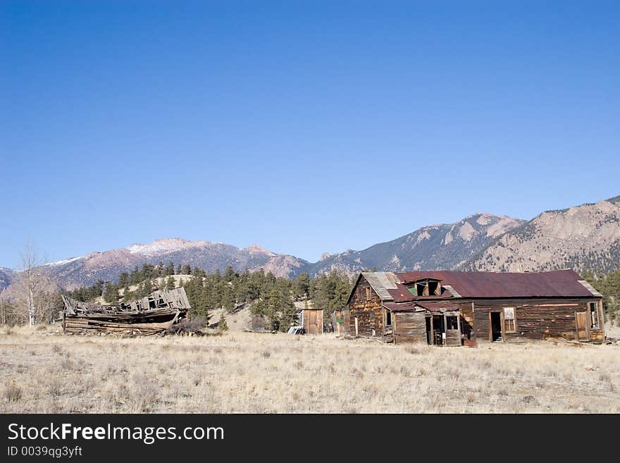 An old, abandoned and falling mining/ranch boardinghouse in Tarryall, Colorado, with the Rocky Mountains in the background. An old, abandoned and falling mining/ranch boardinghouse in Tarryall, Colorado, with the Rocky Mountains in the background.