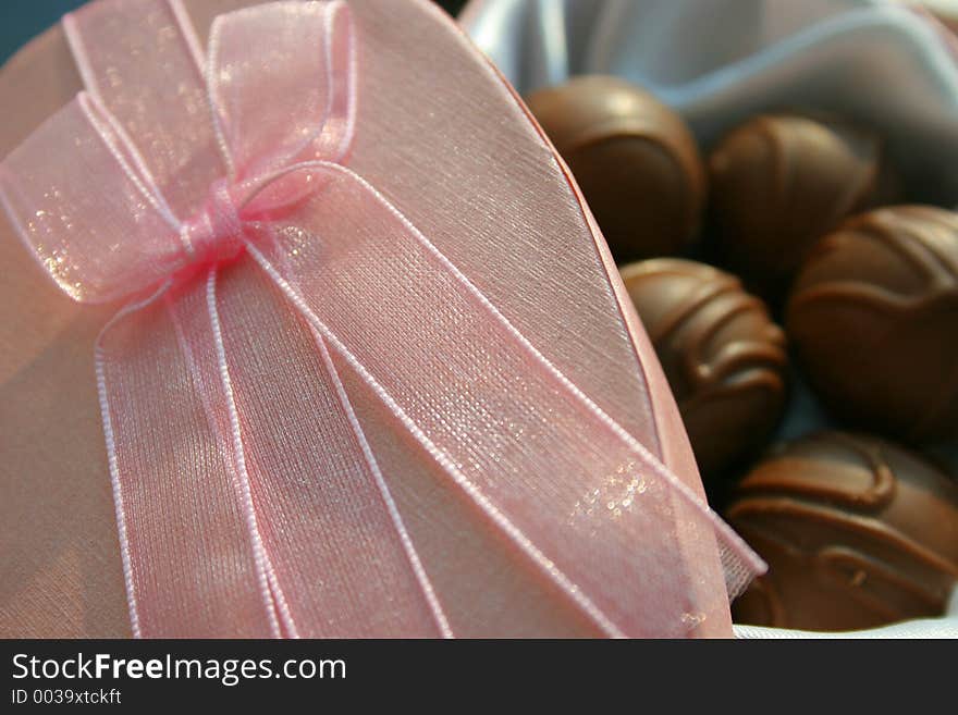 Pink gift box lid with chocolates in the background. Pink gift box lid with chocolates in the background.