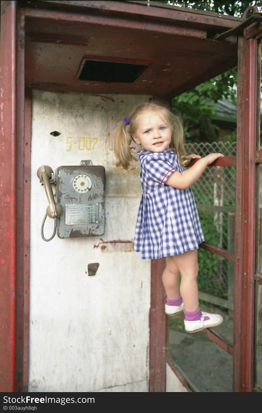 Portrait of the pretty girl standing on the horizontal bar in the phone booth. Portrait of the pretty girl standing on the horizontal bar in the phone booth