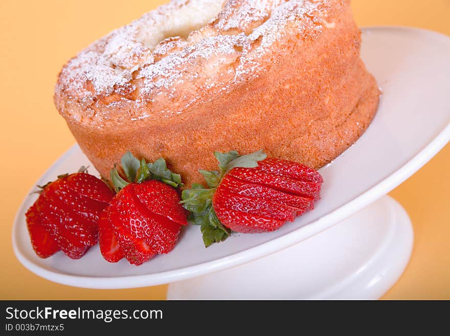 Strawberries cut into decorative fans around the base of an angel food cake dusted with powdered sugar. Strawberries cut into decorative fans around the base of an angel food cake dusted with powdered sugar