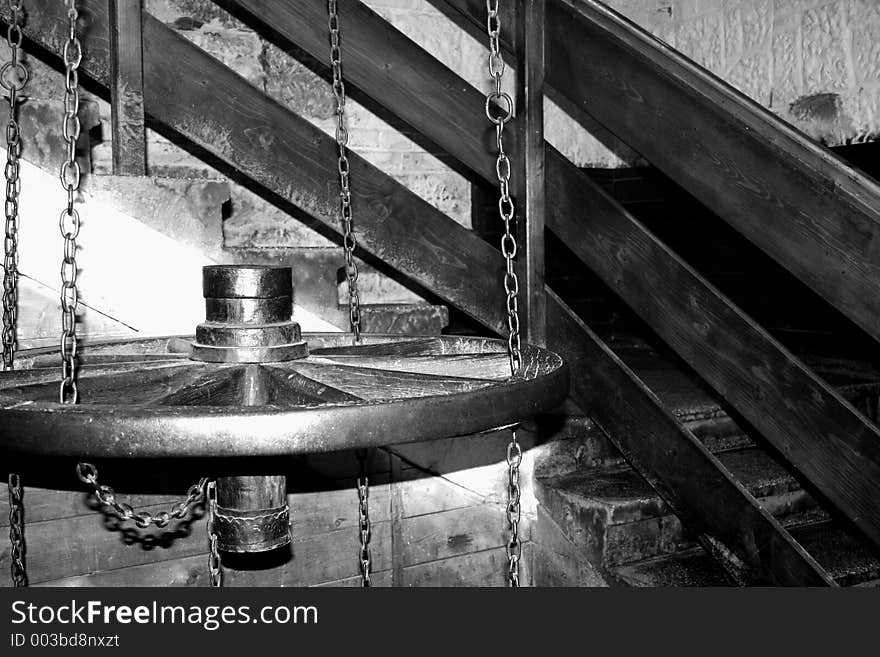 A wagon wheel hung by some chains in a staircase