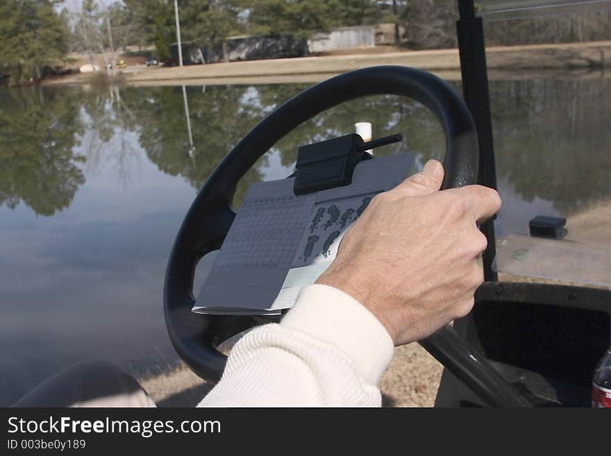 Driving golf cart to the next hole with score card visible. Driving golf cart to the next hole with score card visible.