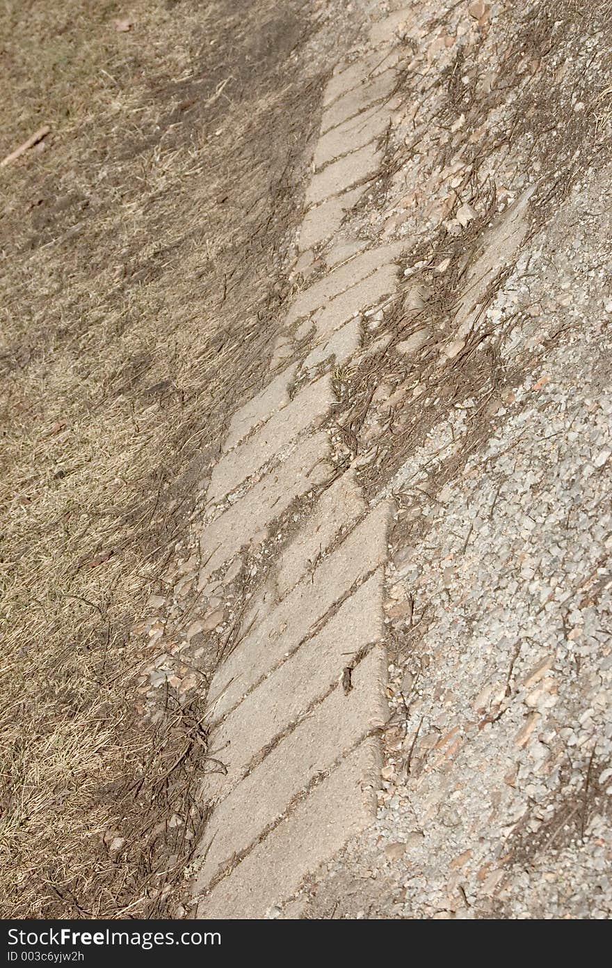 A bit of road reinforced with old concrete blocks, dirt on one side, gravel on the other. A bit of road reinforced with old concrete blocks, dirt on one side, gravel on the other