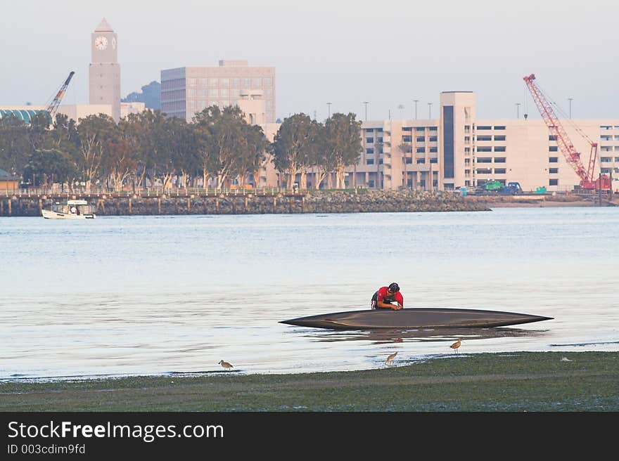 Canoer wrestles canoe out of the water after paddling on San Diego Bay. (Coronado, CA). Canoer wrestles canoe out of the water after paddling on San Diego Bay. (Coronado, CA)