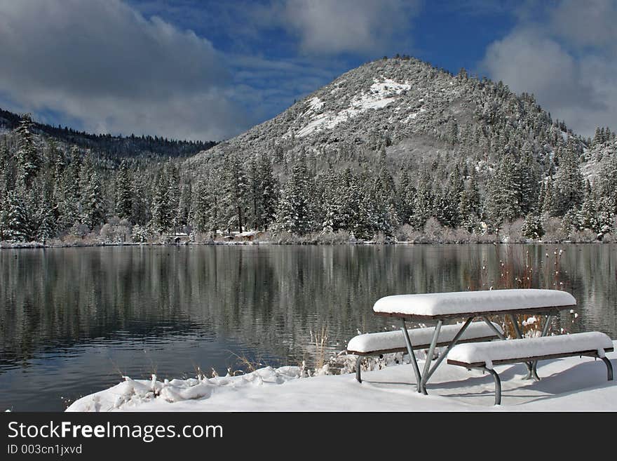 Fresh snow covers picnic table near mountain lake in the Southern Sierras. Fresh snow covers picnic table near mountain lake in the Southern Sierras