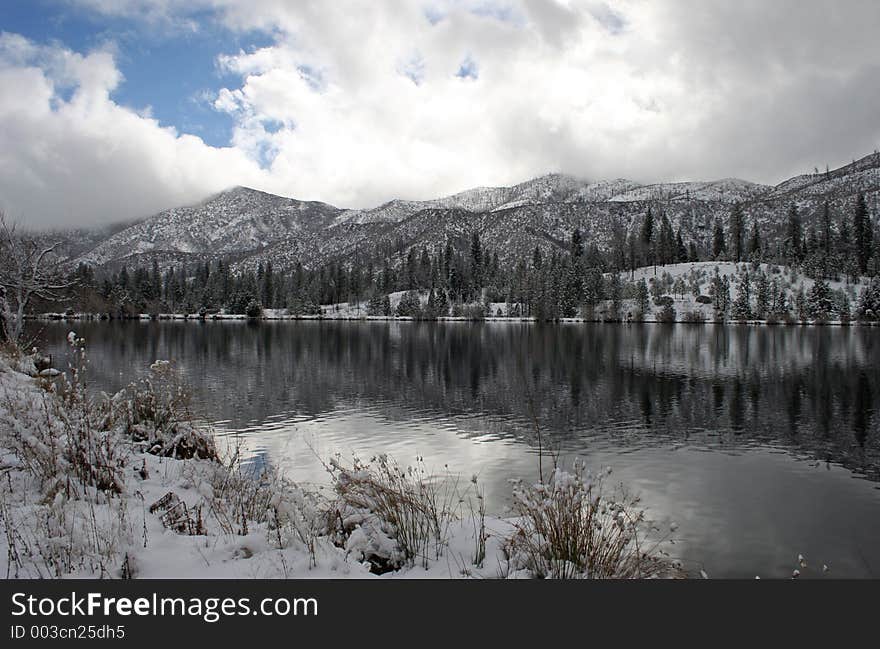 Winter clouds and snow on mountains reflected in mountain lake. Winter clouds and snow on mountains reflected in mountain lake