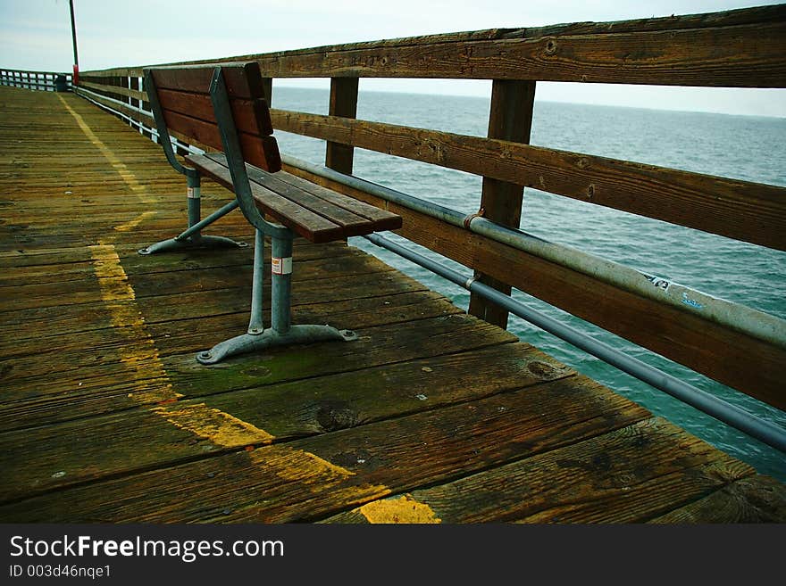 A lone bench on a long wharf looking out to sea. A lone bench on a long wharf looking out to sea.
