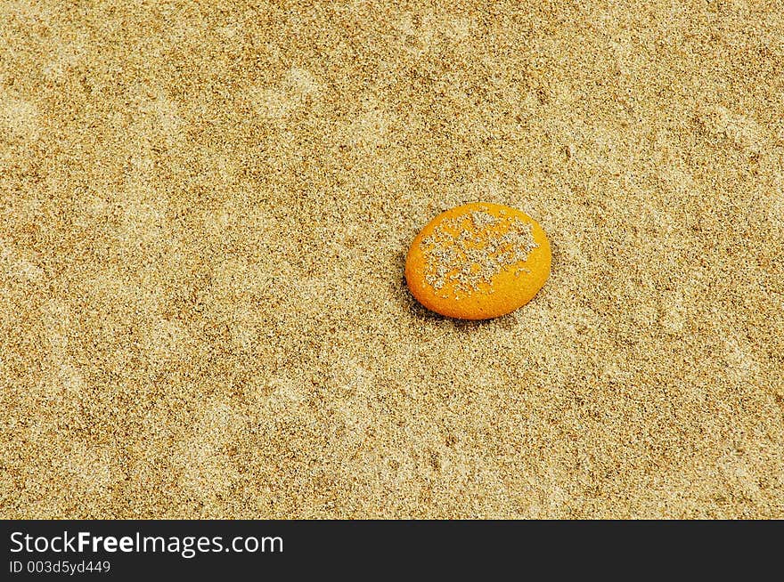 Lone yellow pebble on a sandy beach