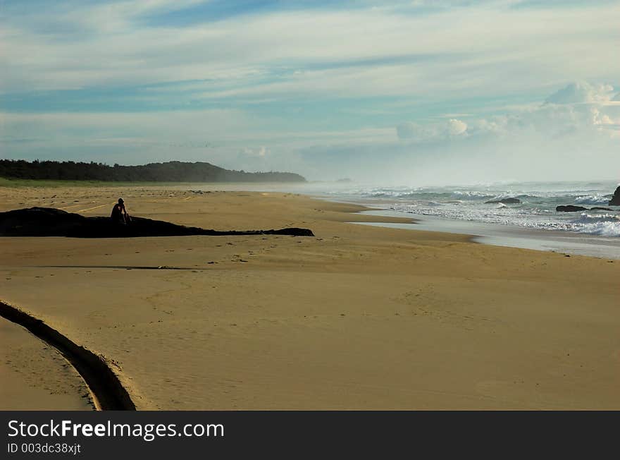 Lone man sitting on the beach in the early morning. Lone man sitting on the beach in the early morning