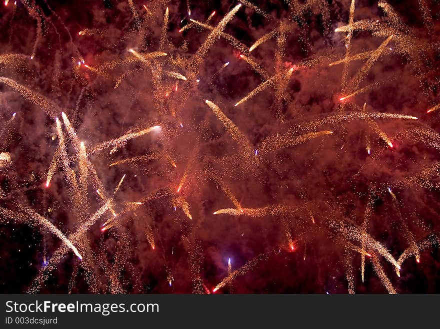 Red and white fireworks spark up the night sky. Red and white fireworks spark up the night sky.