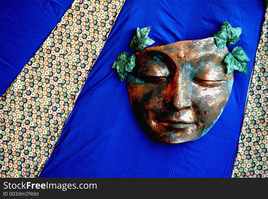 Copper mask with leaves on hand made quilt