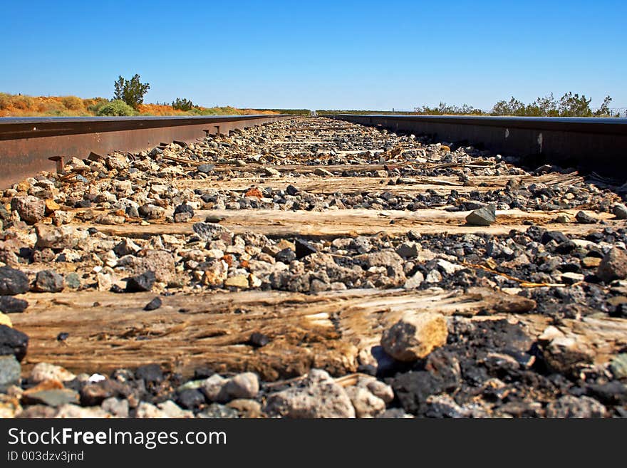 A mouse eye view of a long straight railroad track in the Mojave desert. A mouse eye view of a long straight railroad track in the Mojave desert.