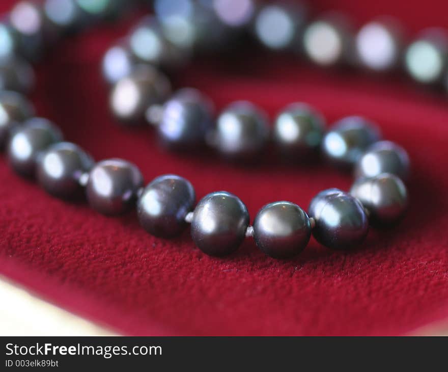 Close up of a black pearl necklace on red velvet